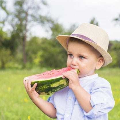 boy eats watermelon on lawn